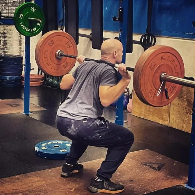 A member in a heavy back squat at Axe & Dagger Fitness gym in Bulkington